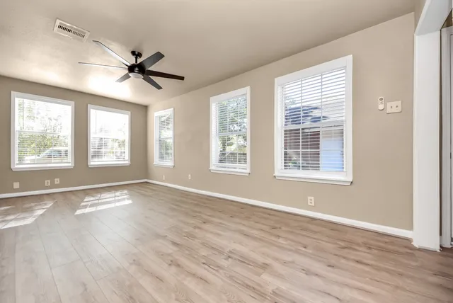 a view of an empty room with a window and wooden floor