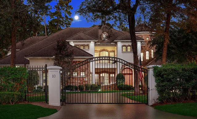 a view of a brick house with large windows and a small yard