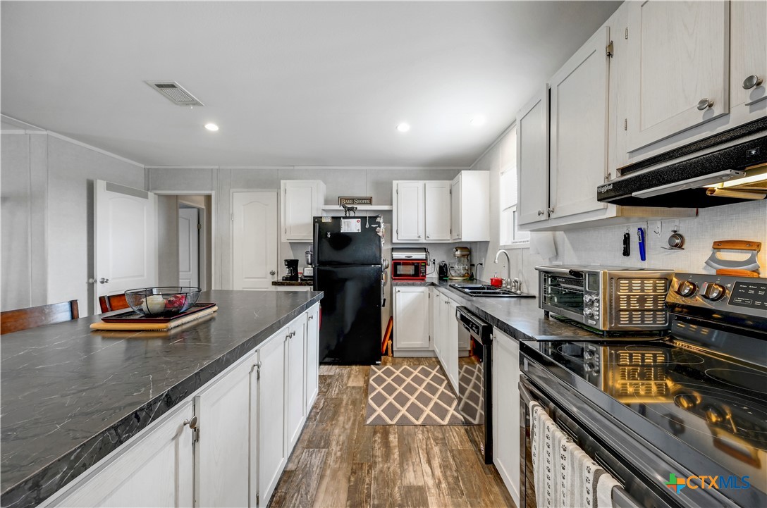 2283 Schwab Road Seguin, TX 78155 - Photo 25 of 40 a kitchen with stainless steel appliances a stove a sink dishwasher a refrigerator and cabinets with wooden floor