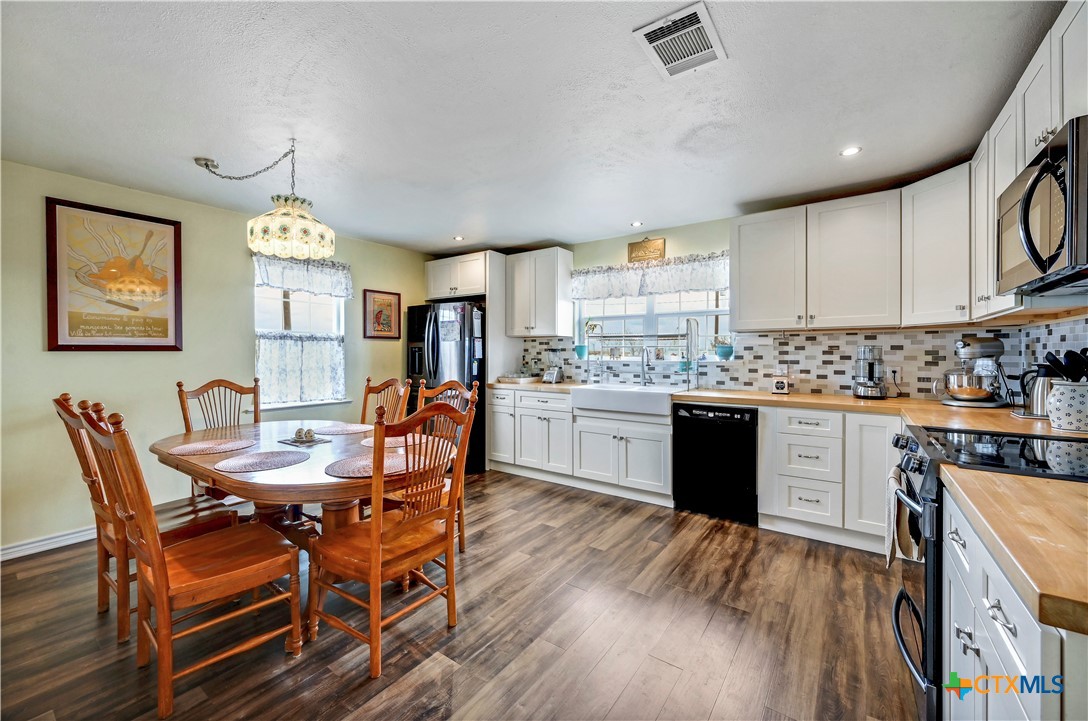 2283 Schwab Road Seguin, TX 78155 - Photo 7 of 40 a kitchen with stainless steel appliances granite countertop a stove top oven a sink dishwasher a dining table and chairs with wooden floor