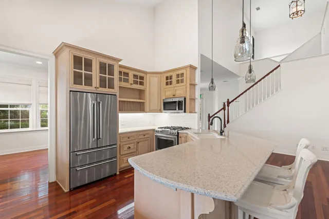 an empty room with wooden floor chandelier and windows