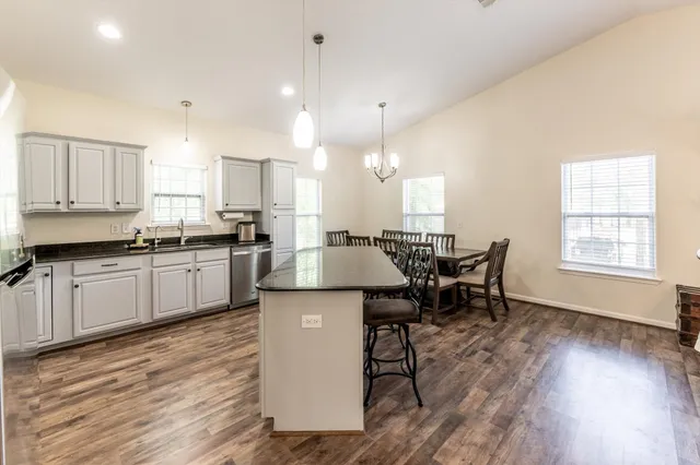 a kitchen with stainless steel appliances kitchen island granite countertop a sink cabinets and wooden floor