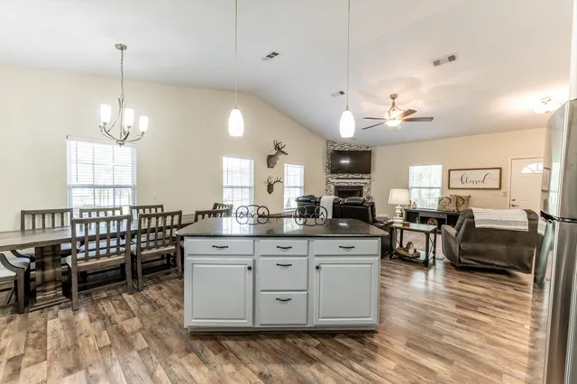 a kitchen with stainless steel appliances granite countertop a stove a sink a dining table and chairs with wooden floor