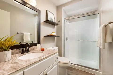 a bathroom with a granite countertop sink toilet and shower