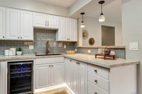 a kitchen with granite countertop a sink white cabinets and stainless steel appliances