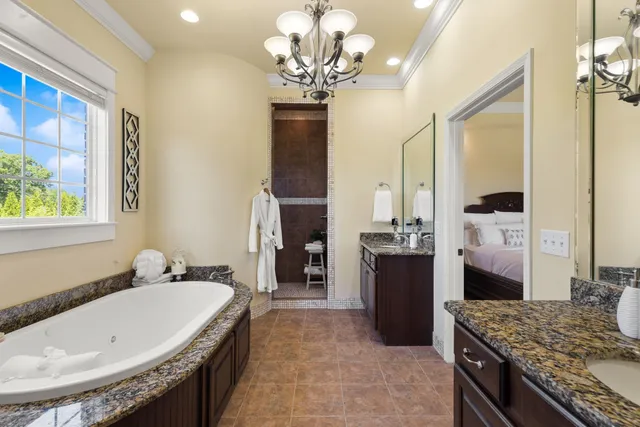 a spacious bedroom with a bed and a lamp on a dresser