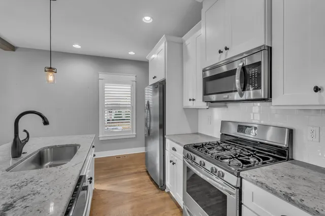 a kitchen with stainless steel appliances granite countertop a sink dishwasher and a wooden floor