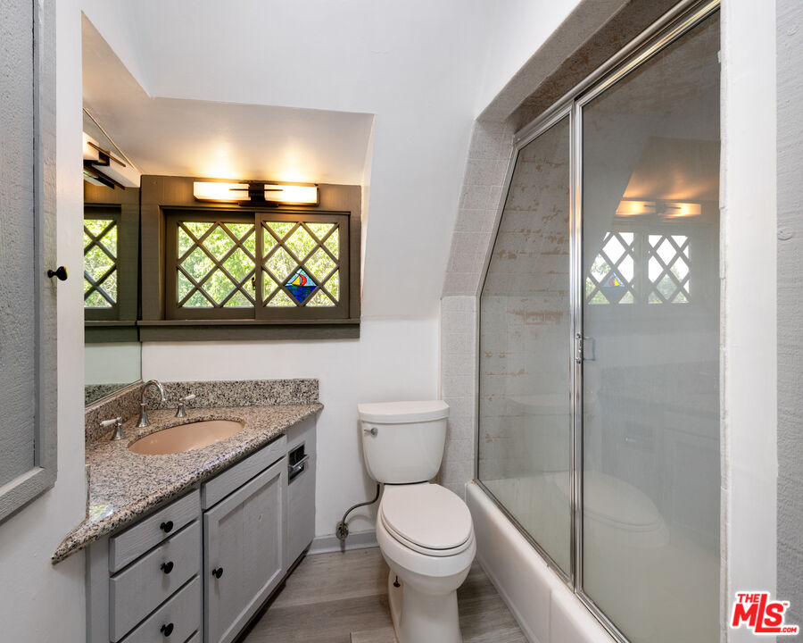 1954 Hillcrest Road, Unit 3 Los Angeles, CA 90068 - Photo 23 of 26 a bathroom with a granite countertop toilet a sink and a large mirror
