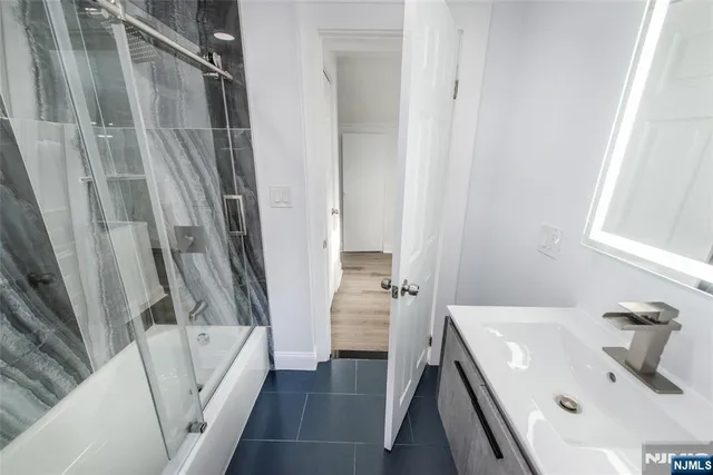 a bathroom with a sink a glass door and a bathtub
