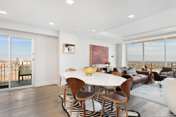 a living room with furniture large windows and wooden floor