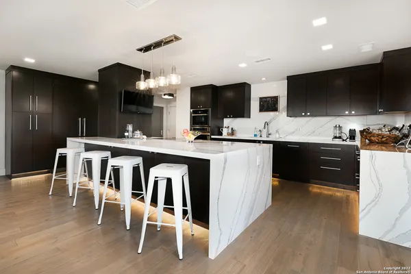 a kitchen with kitchen island a sink and a stove top oven with wooden floor