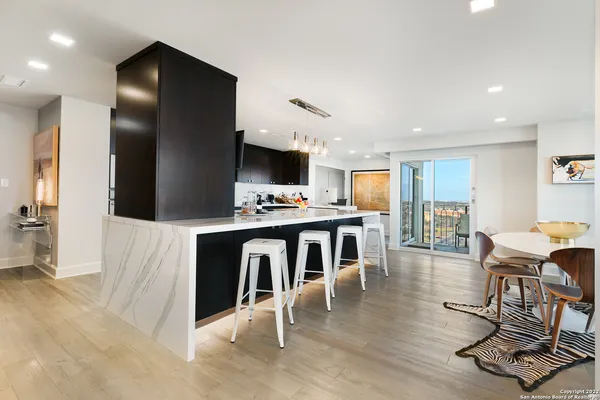a kitchen with stainless steel appliances kitchen island granite countertop a table chairs and a refrigerator