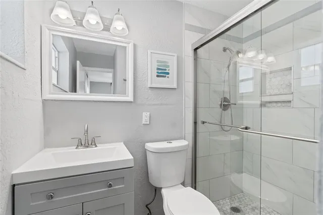 a bathroom with a toilet a sink shower and mirror