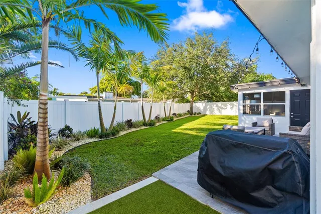 a view of a backyard with table and chairs potted plants and palm tree