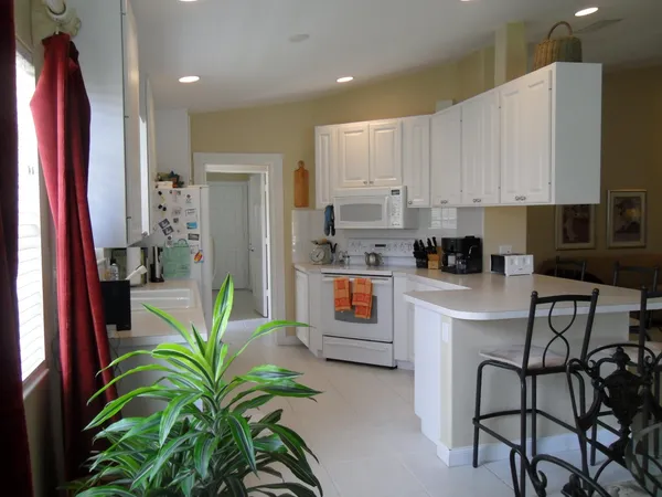 a kitchen with stainless steel appliances a white table chairs and a refrigerator