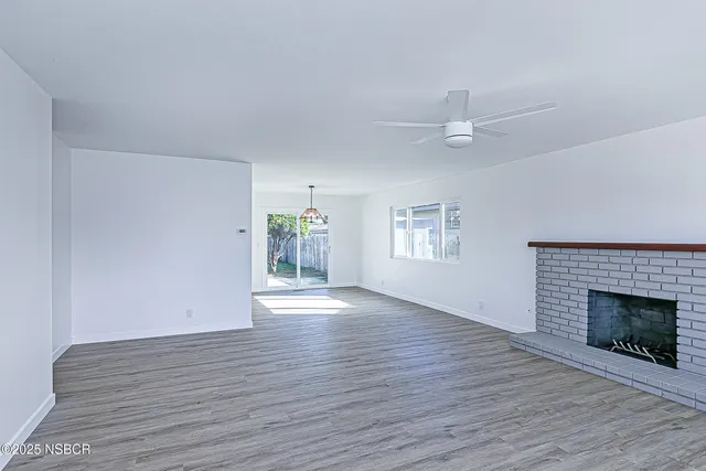 an empty room with wooden floor fireplace and windows