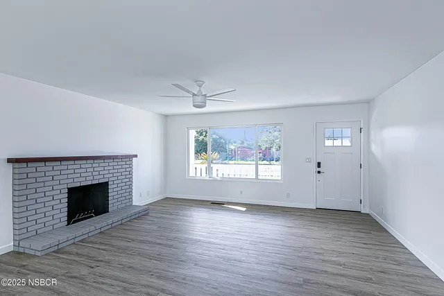 an empty room with wooden floor fireplace and windows