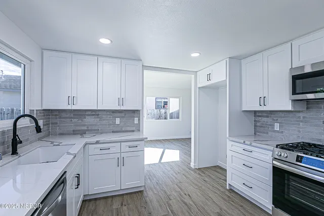 a kitchen with white cabinets stainless steel appliances and sink
