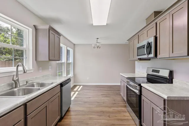 a kitchen with stainless steel appliances granite countertop a sink stove microwave and refrigerator