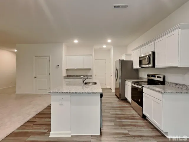 a large kitchen with granite countertop a large counter top stainless steel appliances and cabinets