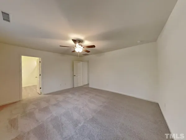 an empty room with a chandelier fan and windows