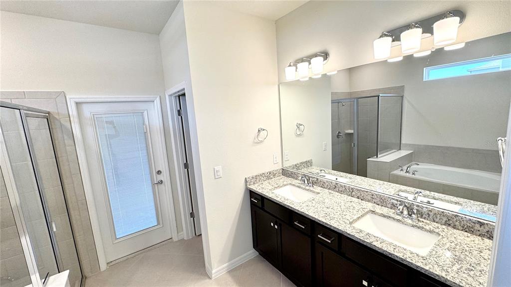 16248 St Kitts Circle Clermont, FL 34714 - Photo 12 of 27 a bathroom with a granite countertop sink a large mirror and a shower