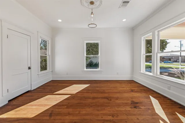 a view of an empty room with a window and wooden floor