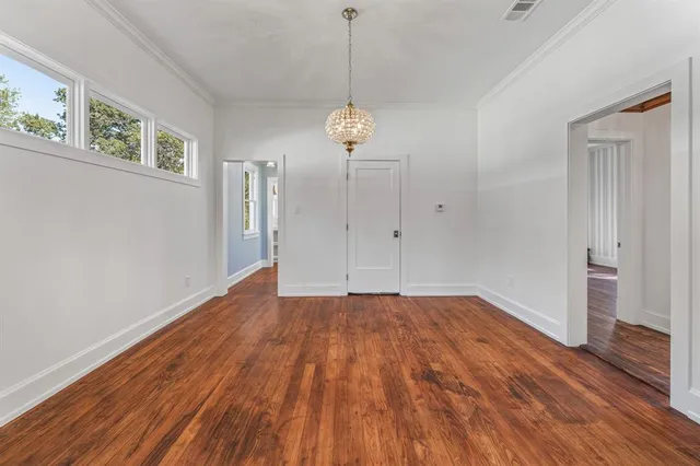 a view of an empty room with wooden floor and window