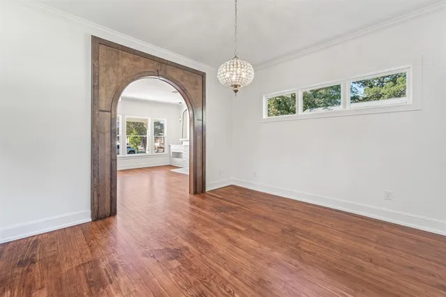 a view of a room with wooden floor chandelier and a window