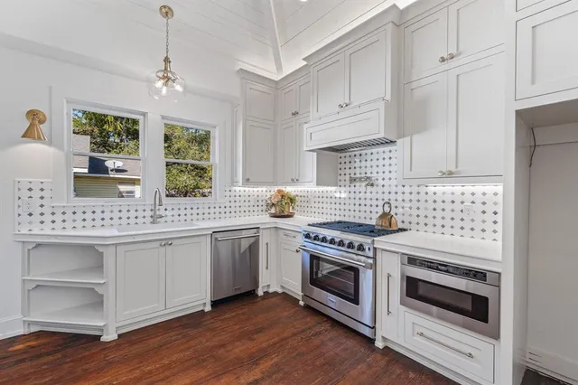 a kitchen with stainless steel appliances white cabinets and a wooden floors