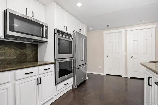 a kitchen with stainless steel appliances white cabinets a stove top oven with wooden floor