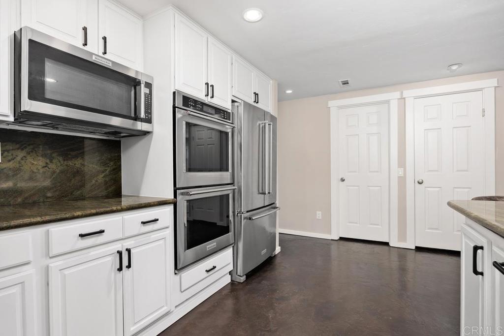 3112 Del Rey Avenue Carlsbad, CA 92009 - Photo 13 of 34 a kitchen with stainless steel appliances white cabinets a stove top oven with wooden floor