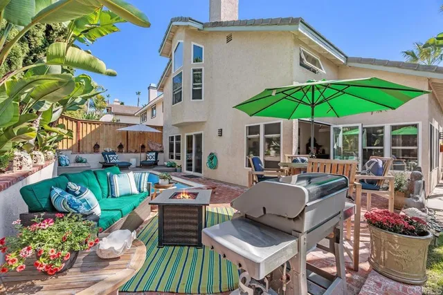 a view of a patio with couches table and chairs under an umbrella