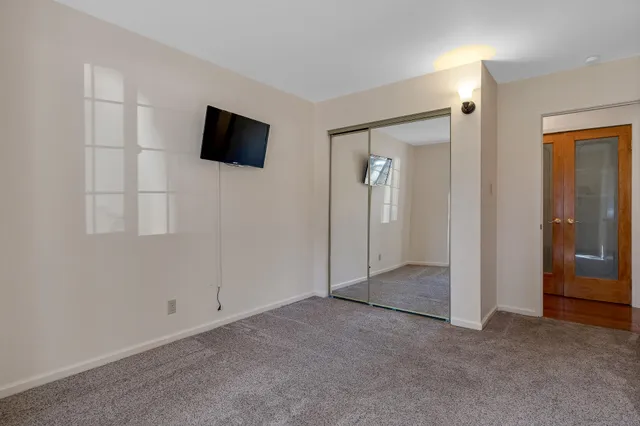 an empty room with mirror and a bathroom