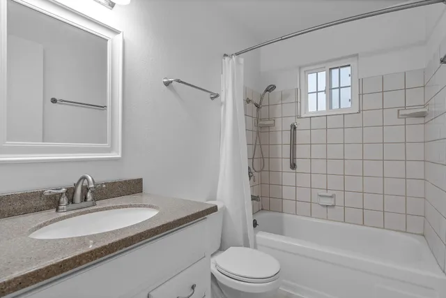 a bathroom with a granite countertop sink toilet and shower