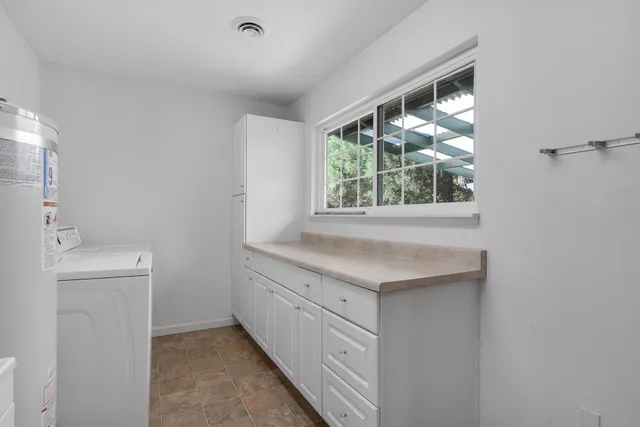 a bathroom with a granite countertop sink a toilet and a window