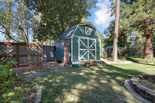 a view of a wooden house with a yard and large trees