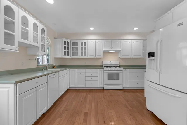 a kitchen with granite countertop white cabinets and white appliances