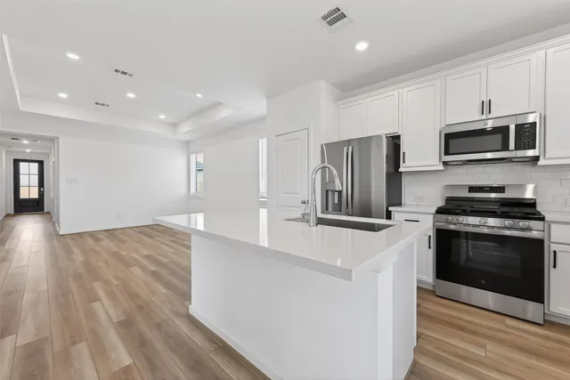 a kitchen with stainless steel appliances a stove a sink a microwave a refrigerator and cabinets