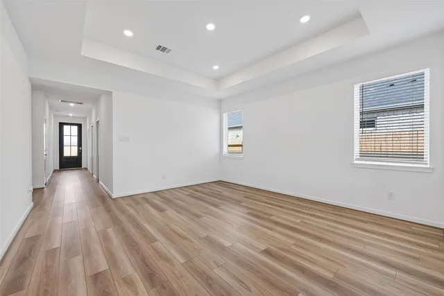 a view of empty room with wooden floor and fan