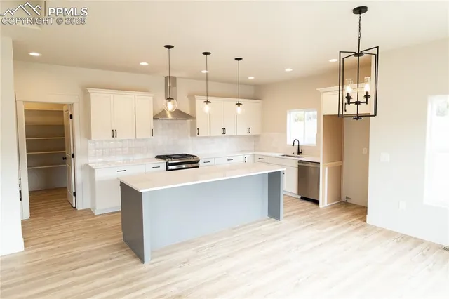 a kitchen with stainless steel appliances kitchen island a refrigerator sink and cabinets