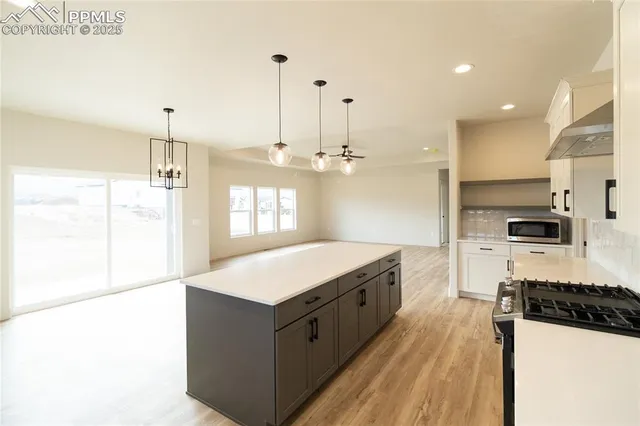 a large kitchen with kitchen island a stove a sink a refrigerator and a granite counter tops