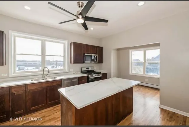 a kitchen with stainless steel appliances a sink a stove a refrigerator cabinets and a window