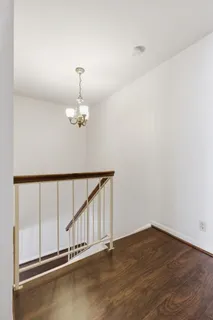 an empty room with wooden floor fan and window