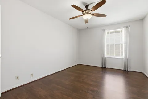 an empty room with wooden floor and ceiling fan