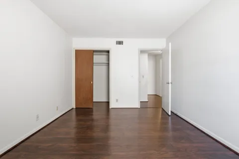 an empty room with wooden floor and closet