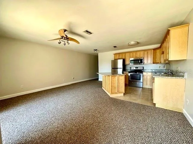a view of a kitchen with kitchen island a sink wooden floor and stainless steel appliances