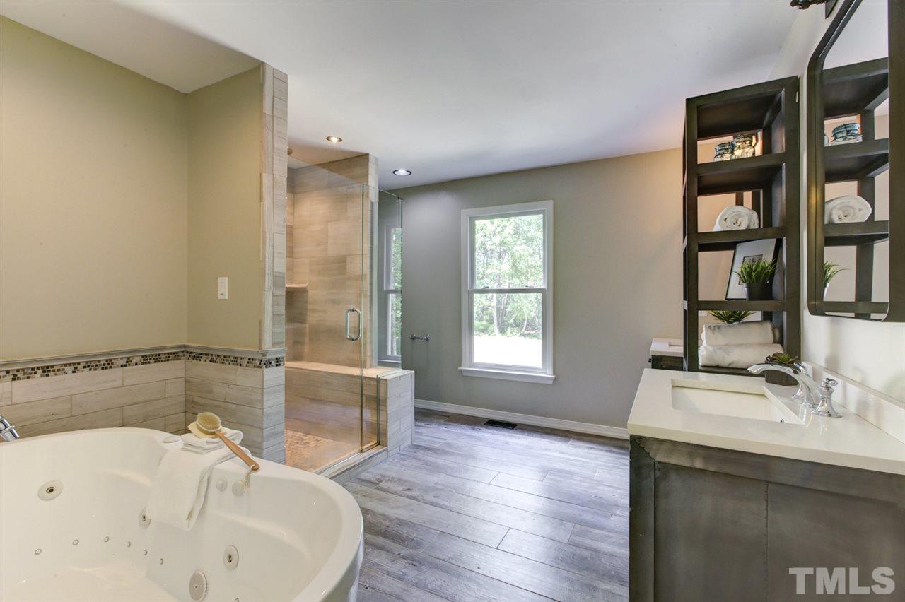 8228 Ridgeback Road Apex, NC 27523 - Photo 16 of 30 a bathroom with a tub sink and mirror
