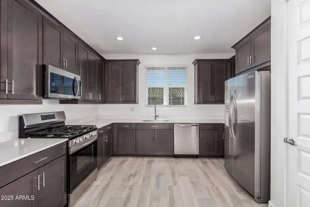 a kitchen with stainless steel appliances granite countertop a stove top oven a sink dishwasher a refrigerator and cabinets with wooden floor