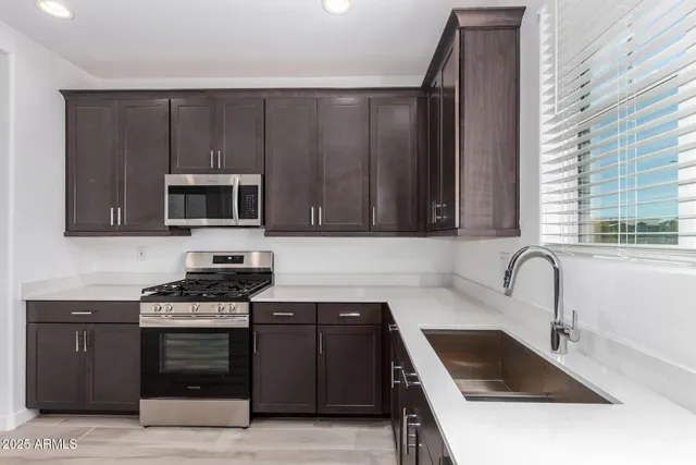 a kitchen with granite countertop a stove a sink and a microwave